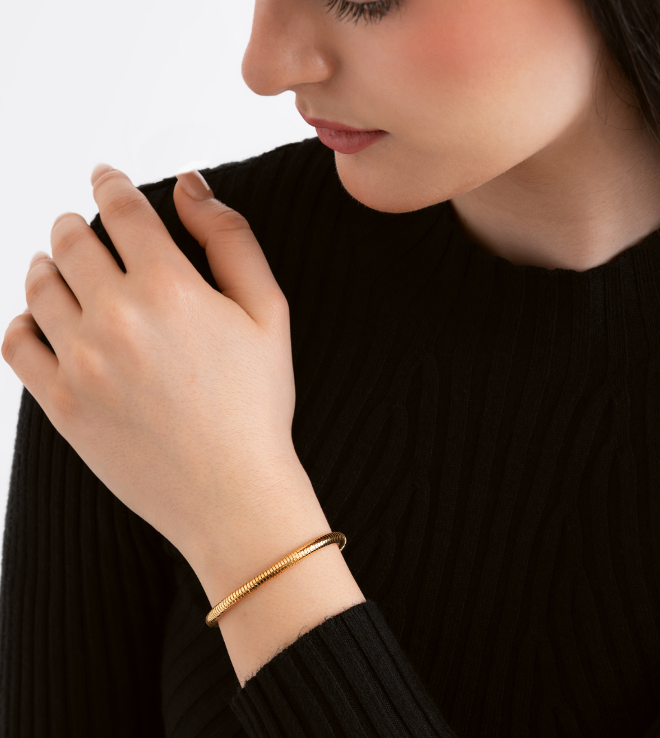 Woman wearing a gold bracelet on a plain background