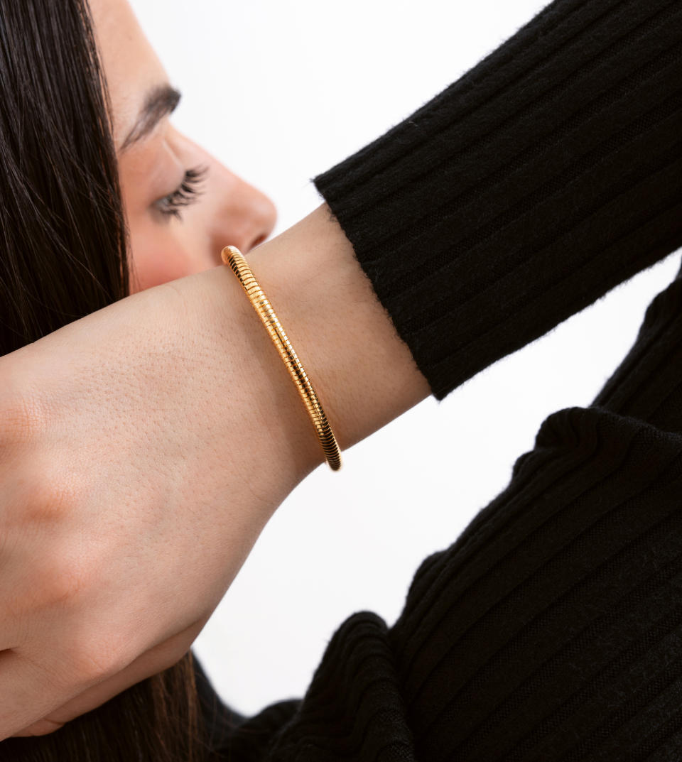 Woman wearing a gold bracelet on a white background