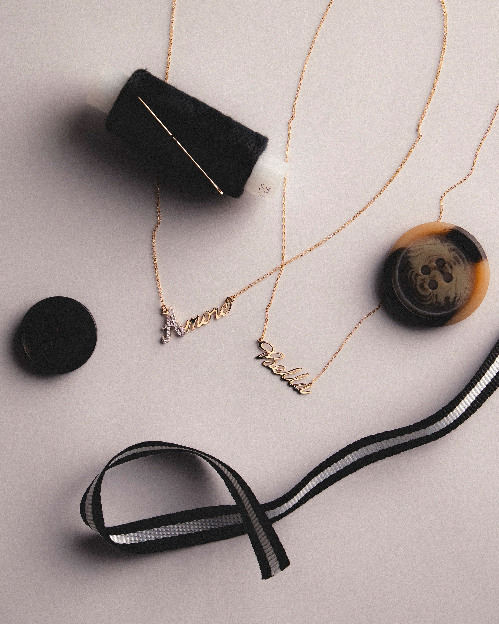 18k Gold name necklaces with diamonds on a light gray surface